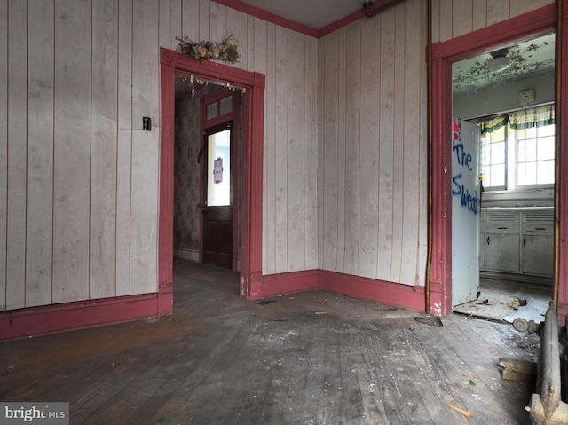 unfurnished room with wood walls and dark hardwood / wood-style floors