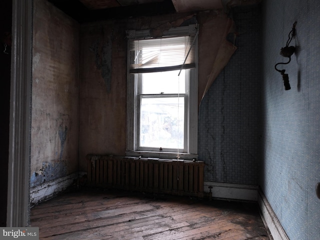 spare room featuring radiator heating unit and hardwood / wood-style floors