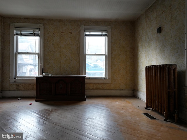 spare room with a wealth of natural light, radiator heating unit, and light hardwood / wood-style floors