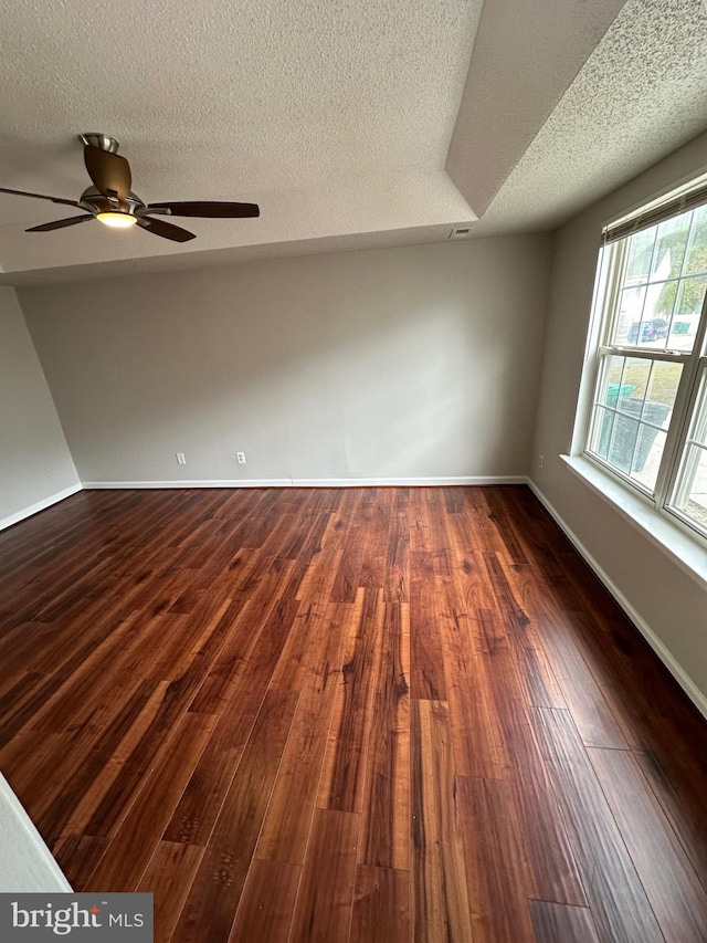 unfurnished room with a textured ceiling, ceiling fan, and dark wood-type flooring