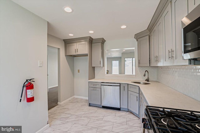 kitchen with gray cabinets, stainless steel appliances, sink, and tasteful backsplash