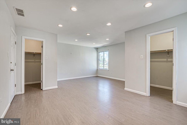 unfurnished bedroom featuring a closet, light wood-type flooring, and a walk in closet