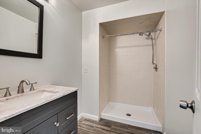 bathroom featuring vanity, wood-type flooring, and tiled shower