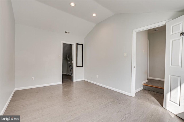 spare room featuring light wood-type flooring and vaulted ceiling