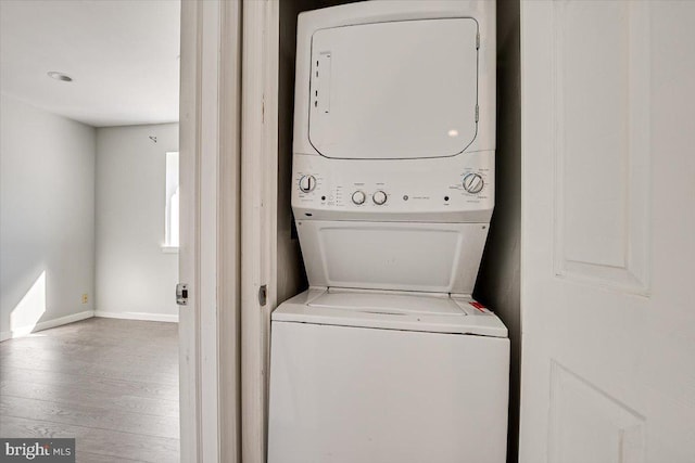 laundry area featuring stacked washer and clothes dryer and hardwood / wood-style flooring