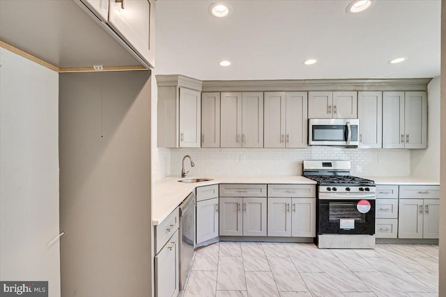 kitchen with gray cabinets, decorative backsplash, sink, and stainless steel appliances