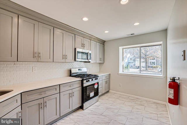 kitchen featuring gray cabinetry, backsplash, and appliances with stainless steel finishes