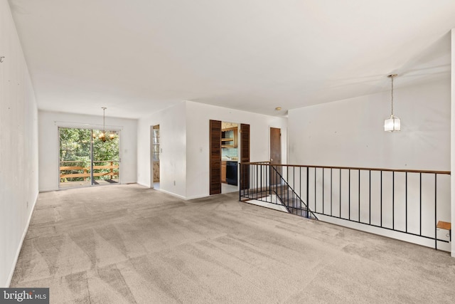 unfurnished room featuring a notable chandelier and light carpet