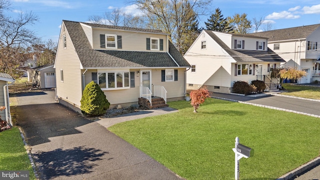 front facade with a garage, an outbuilding, and a front yard