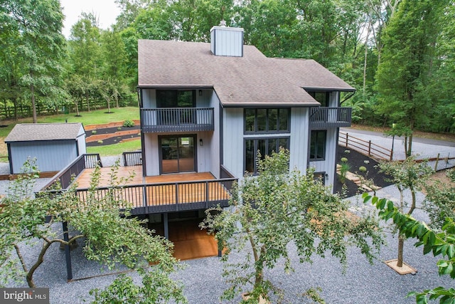 rear view of property featuring a balcony and a deck