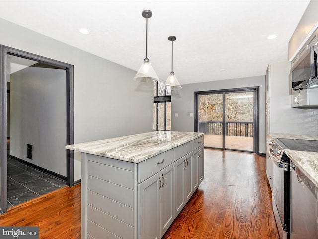 kitchen with appliances with stainless steel finishes, dark hardwood / wood-style flooring, decorative light fixtures, a center island, and gray cabinets