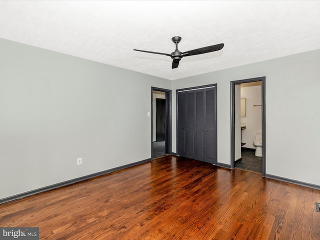 unfurnished bedroom with ceiling fan, a textured ceiling, connected bathroom, dark hardwood / wood-style flooring, and a closet