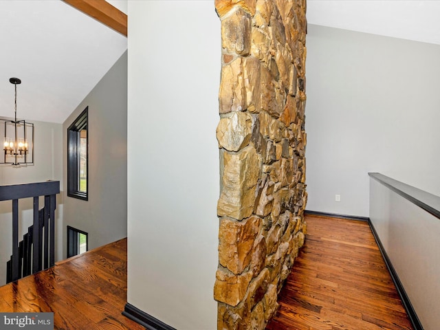 corridor with vaulted ceiling with beams, dark hardwood / wood-style floors, and an inviting chandelier