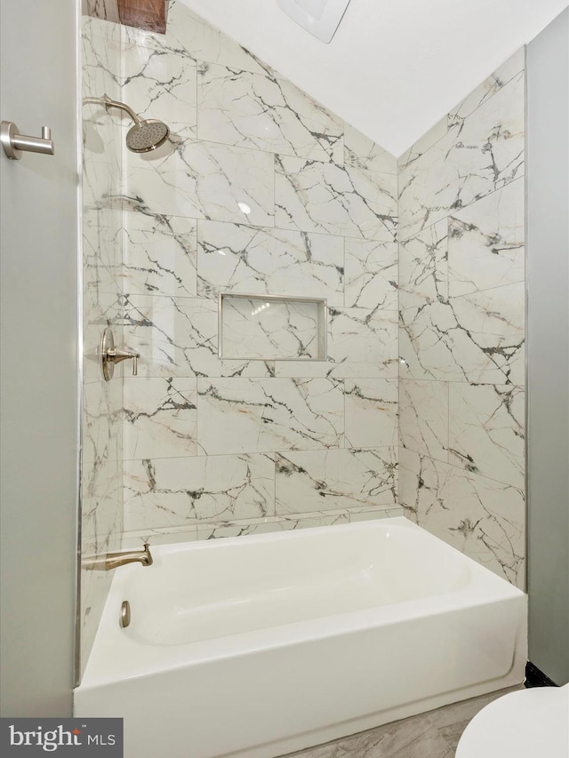 bathroom featuring tiled shower / bath combo and toilet