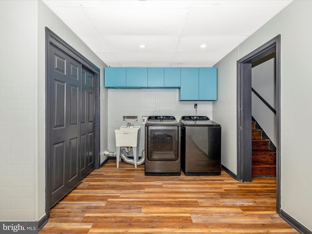 laundry room with washer and dryer, light hardwood / wood-style flooring, cabinets, and sink