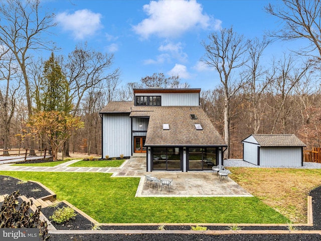 rear view of property featuring a patio area, a yard, and an outbuilding