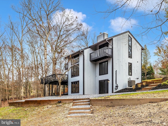 view of side of property featuring cooling unit, a balcony, and a wooden deck