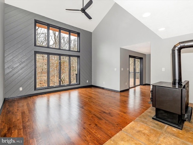 living room featuring hardwood / wood-style floors, ceiling fan, a wood stove, and high vaulted ceiling