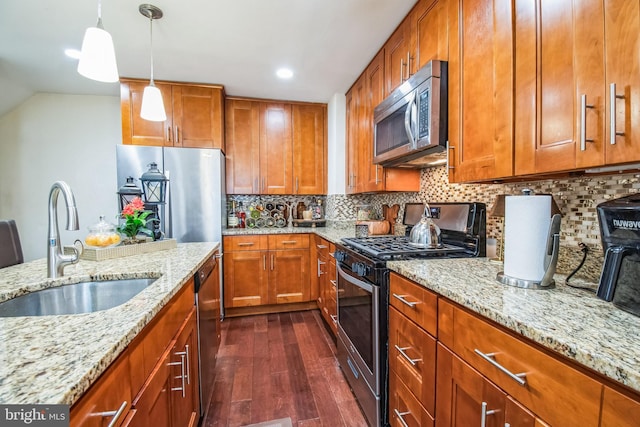 kitchen featuring light stone countertops, pendant lighting, appliances with stainless steel finishes, tasteful backsplash, and sink