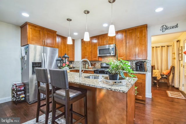 kitchen with sink, decorative light fixtures, backsplash, stainless steel appliances, and light stone counters