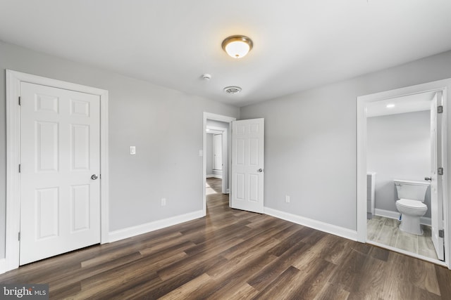 bedroom with dark wood-type flooring and connected bathroom