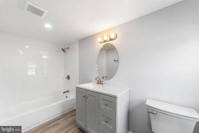 full bathroom with hardwood / wood-style floors, vanity, toilet, and tiled shower / bath