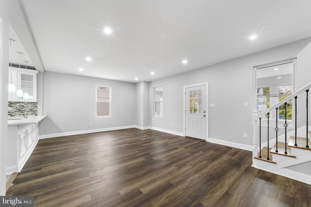 unfurnished living room featuring dark hardwood / wood-style floors and sink