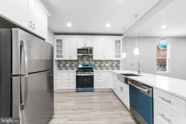 kitchen featuring white cabinets, stainless steel appliances, hanging light fixtures, and sink