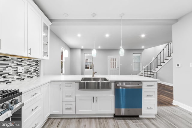 kitchen with white cabinetry, sink, kitchen peninsula, decorative light fixtures, and appliances with stainless steel finishes