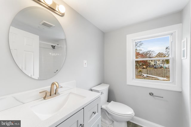 bathroom featuring a shower, vanity, and toilet