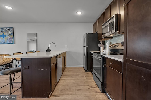 kitchen with kitchen peninsula, a kitchen breakfast bar, stainless steel appliances, and light hardwood / wood-style floors