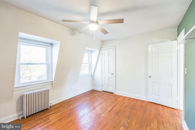 unfurnished bedroom featuring light hardwood / wood-style floors, ceiling fan, and radiator heating unit