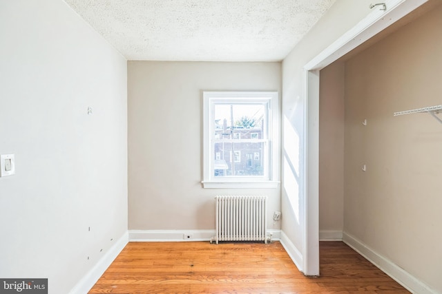 interior space featuring radiator, light wood-type flooring, and a textured ceiling