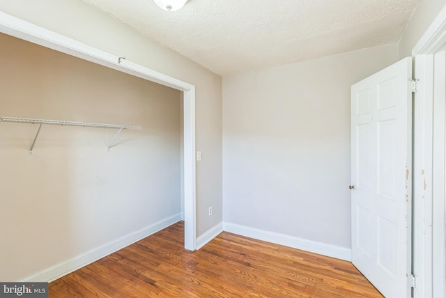 unfurnished bedroom featuring a closet, hardwood / wood-style floors, and a textured ceiling