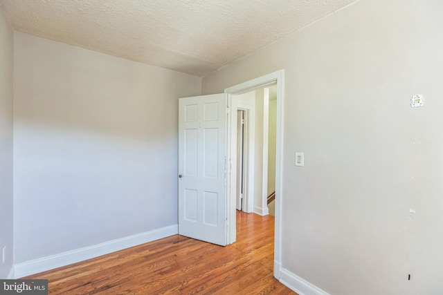 spare room featuring hardwood / wood-style floors and a textured ceiling