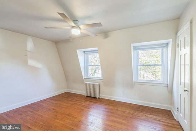 empty room featuring radiator heating unit, hardwood / wood-style floors, and a healthy amount of sunlight