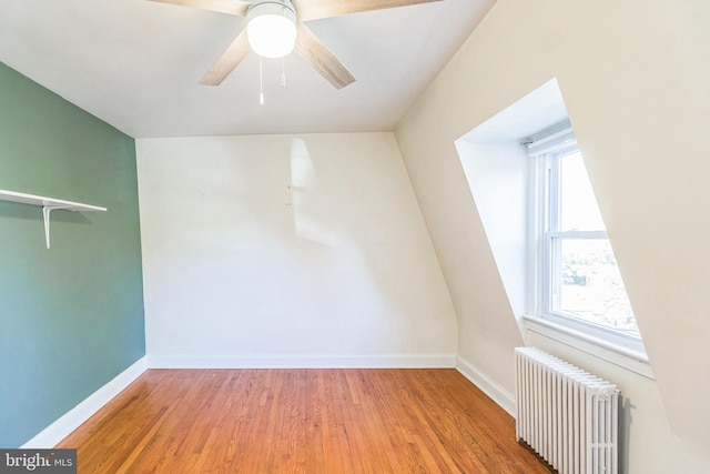 unfurnished room with ceiling fan, radiator, wood-type flooring, and a healthy amount of sunlight