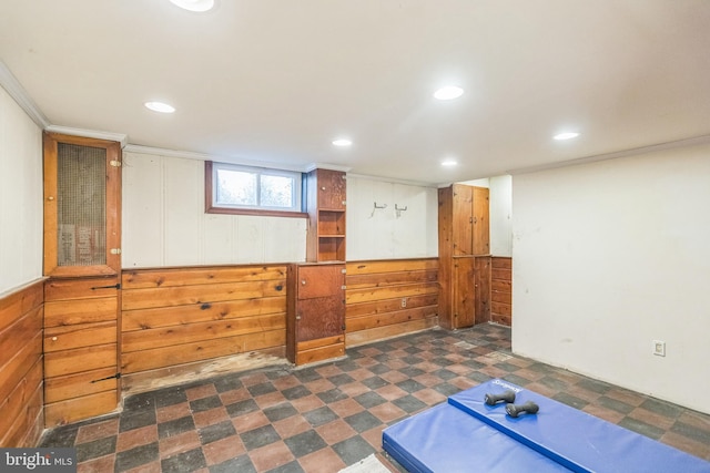 basement with wooden walls and crown molding