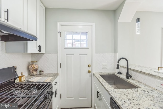 kitchen featuring gas stove, light stone counters, white cabinetry, decorative light fixtures, and sink