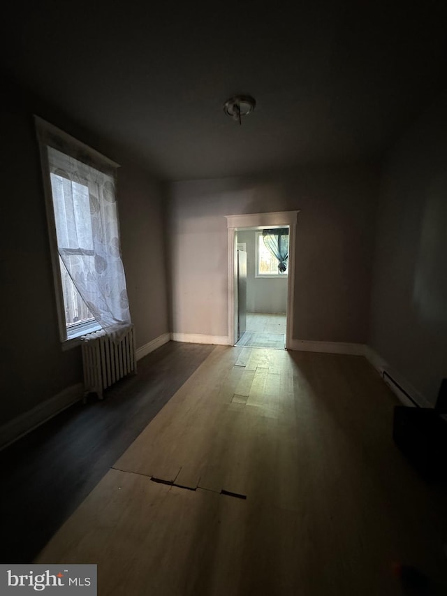 spare room with a baseboard heating unit, radiator heating unit, and dark hardwood / wood-style floors