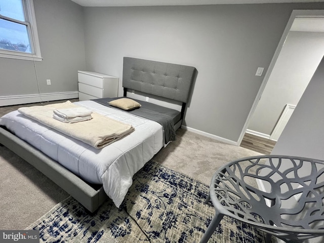 bedroom with hardwood / wood-style floors and a baseboard heating unit