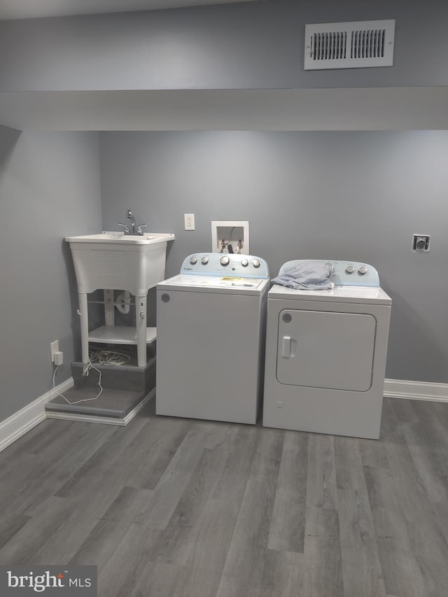 washroom with hardwood / wood-style flooring and washer and dryer