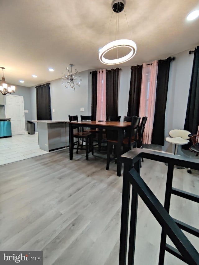 dining area featuring light wood-type flooring and a notable chandelier