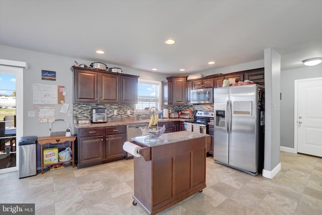 kitchen with sink, a center island, dark brown cabinets, backsplash, and stainless steel appliances