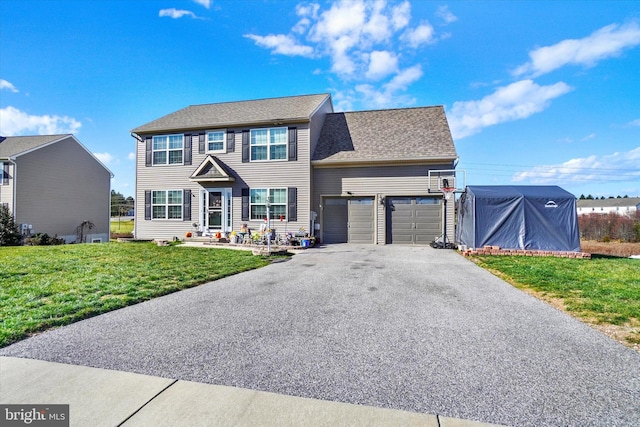 colonial-style house featuring a garage, aphalt driveway, a front yard, and a shingled roof