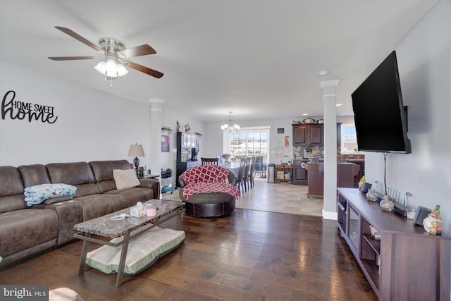 living room featuring ceiling fan with notable chandelier, ornate columns, and dark wood-type flooring