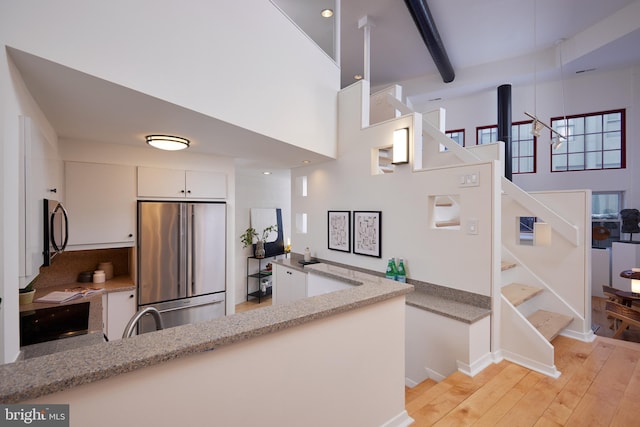 kitchen with white cabinets, high end refrigerator, light stone counters, and beamed ceiling