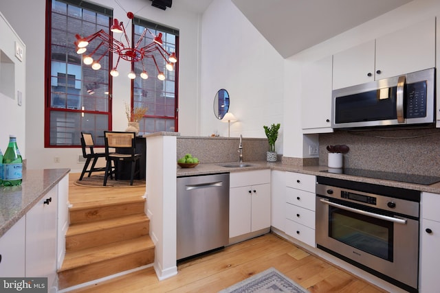 kitchen featuring white cabinets, sink, tasteful backsplash, light hardwood / wood-style floors, and stainless steel appliances