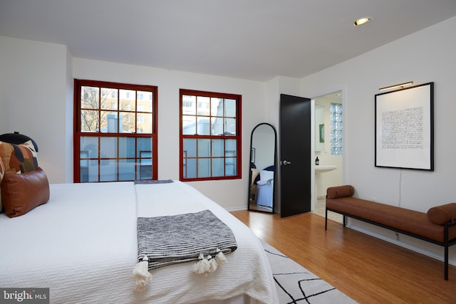 bedroom featuring light wood-type flooring and ensuite bath