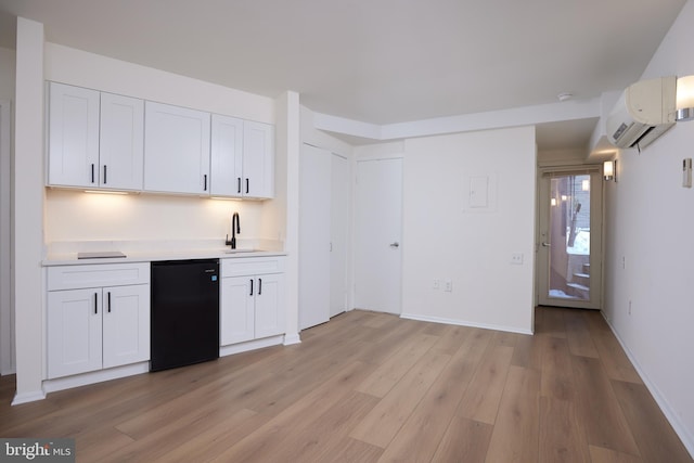 kitchen featuring white cabinetry, sink, light hardwood / wood-style flooring, a wall unit AC, and refrigerator